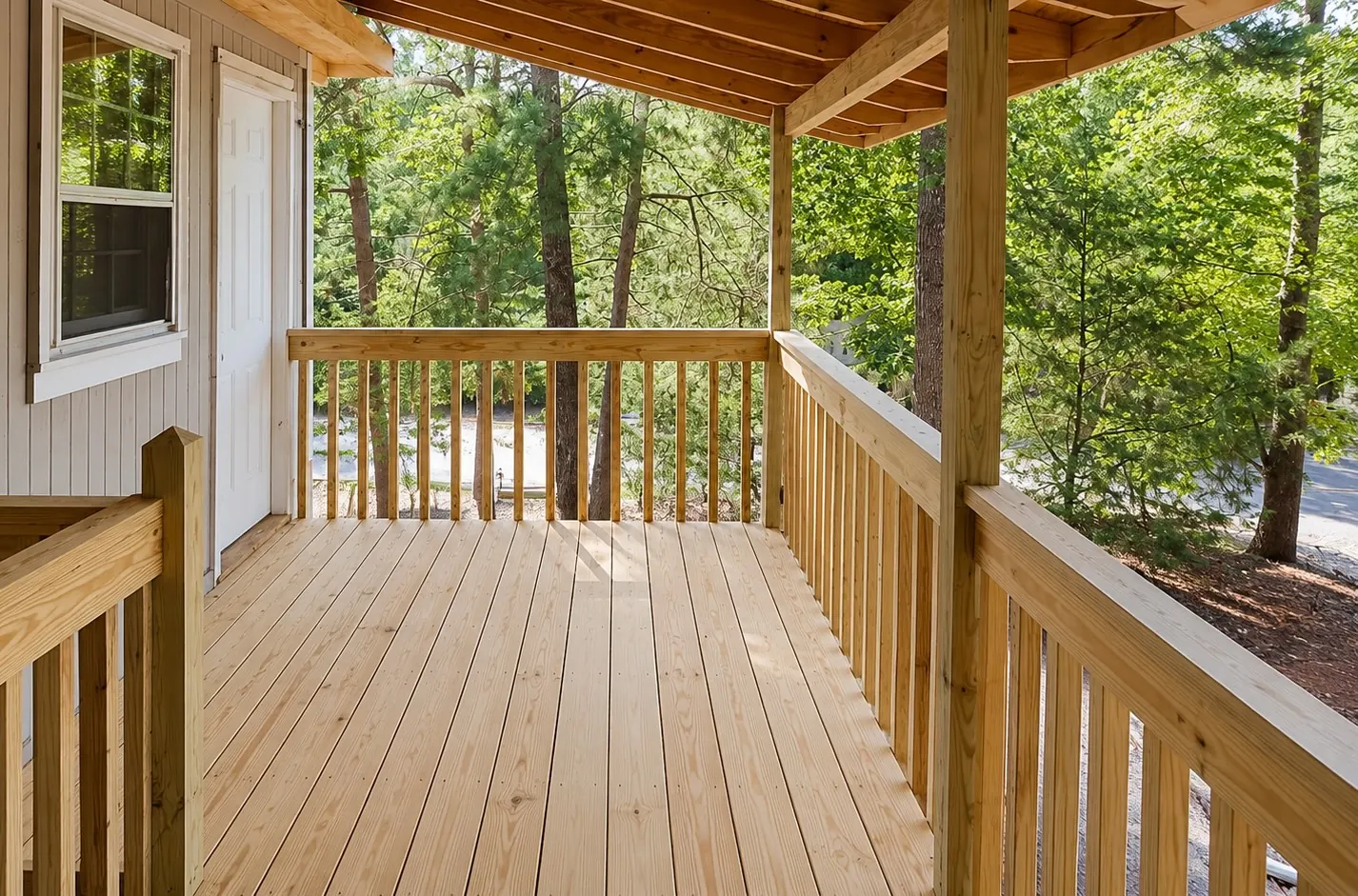 Newly built covered wood deck with railings overlooking trees